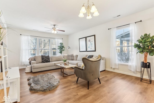 living room featuring ceiling fan with notable chandelier, hardwood / wood-style flooring, and plenty of natural light