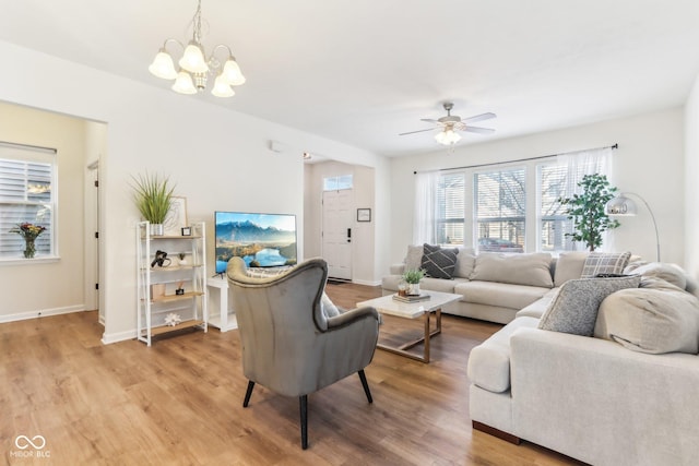 living room featuring ceiling fan with notable chandelier and wood-type flooring