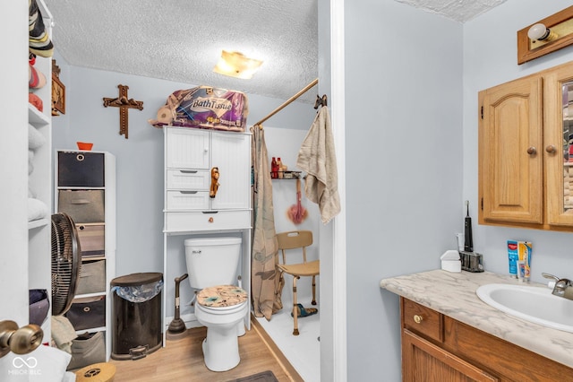 bathroom with a textured ceiling, wood-type flooring, vanity, toilet, and a shower with shower curtain