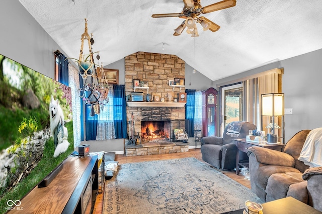 living room with ceiling fan, a textured ceiling, lofted ceiling, and a stone fireplace