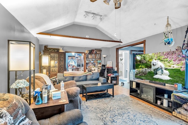 living room featuring ceiling fan, a textured ceiling, track lighting, and vaulted ceiling