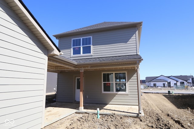 back of property featuring a patio and roof with shingles