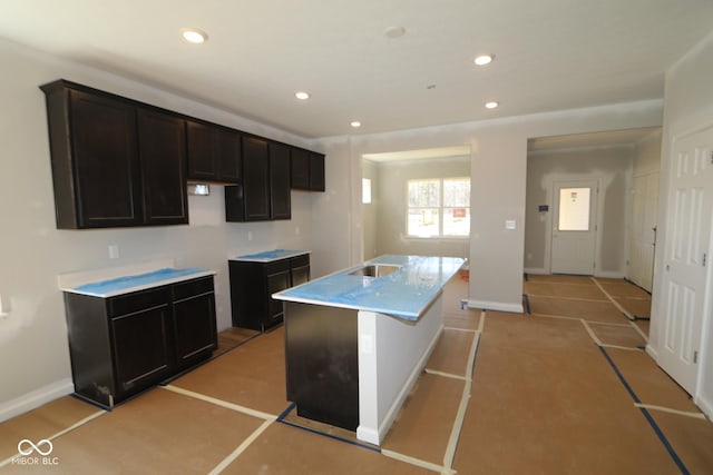 kitchen featuring recessed lighting, a center island with sink, and baseboards