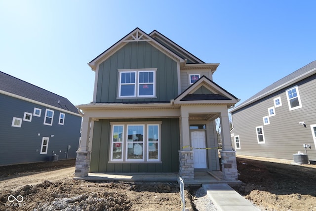 craftsman-style home featuring cooling unit, covered porch, and board and batten siding