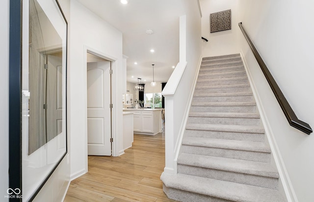 staircase with a chandelier and hardwood / wood-style floors