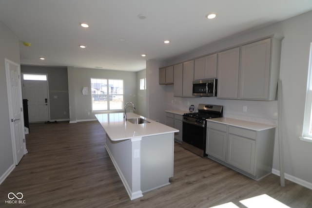 kitchen featuring wood finished floors, recessed lighting, gray cabinets, a sink, and stainless steel appliances