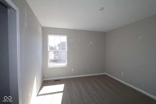 carpeted spare room with visible vents and baseboards