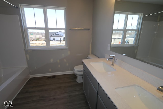 full bathroom with a sink, toilet, wood finished floors, and washtub / shower combination