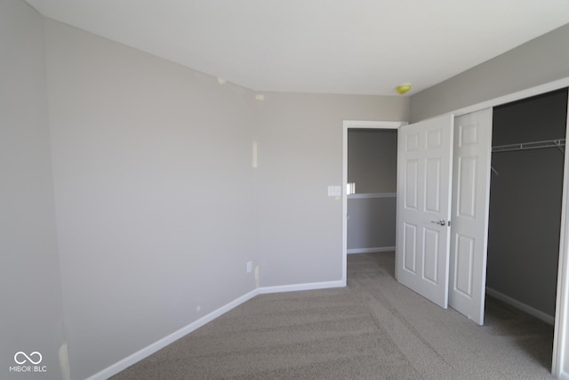 unfurnished bedroom featuring light colored carpet, baseboards, and a closet