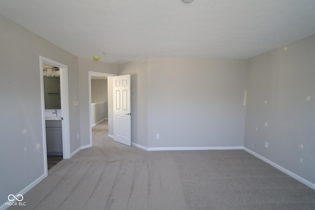 unfurnished room with a sink, baseboards, and light carpet