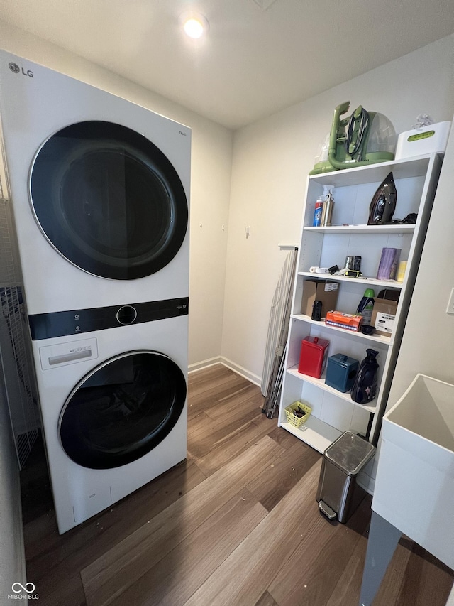 laundry room with stacked washer and dryer and wood-type flooring