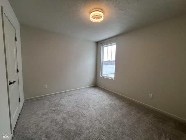 carpeted empty room featuring a textured ceiling