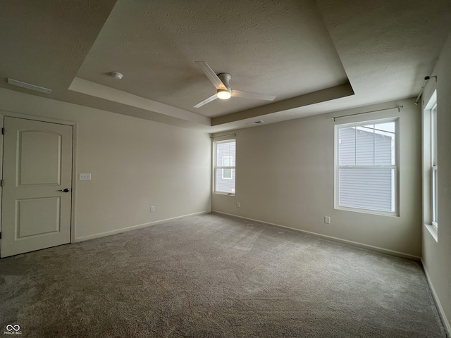 carpeted empty room with a textured ceiling, ceiling fan, and a tray ceiling