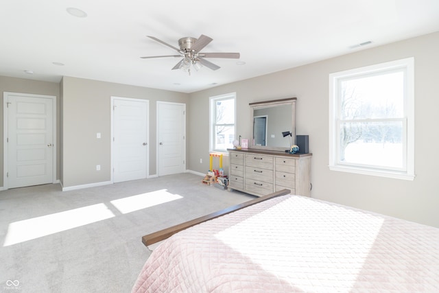 carpeted bedroom with ceiling fan and multiple closets