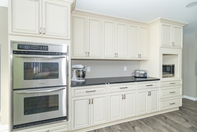 kitchen with cream cabinetry, hardwood / wood-style floors, and appliances with stainless steel finishes