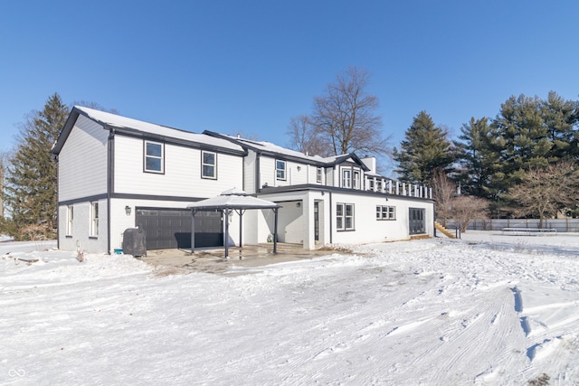 snow covered back of property featuring a garage