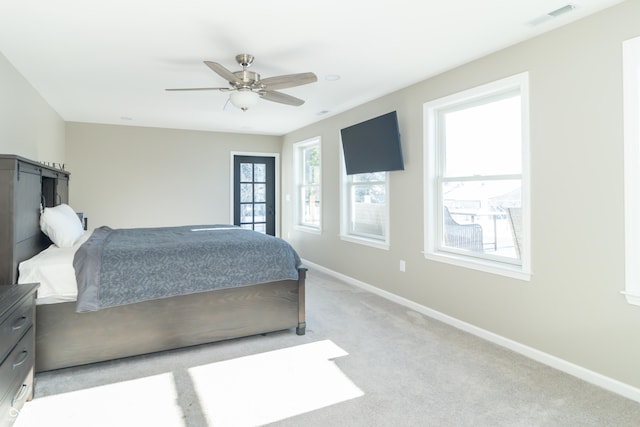 bedroom featuring ceiling fan, light carpet, and multiple windows