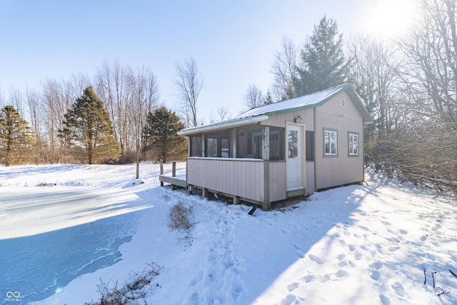 view of snowy exterior featuring a sunroom