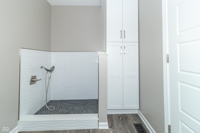 bathroom with hardwood / wood-style floors and tiled shower