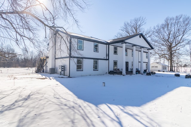 snow covered rear of property featuring central AC