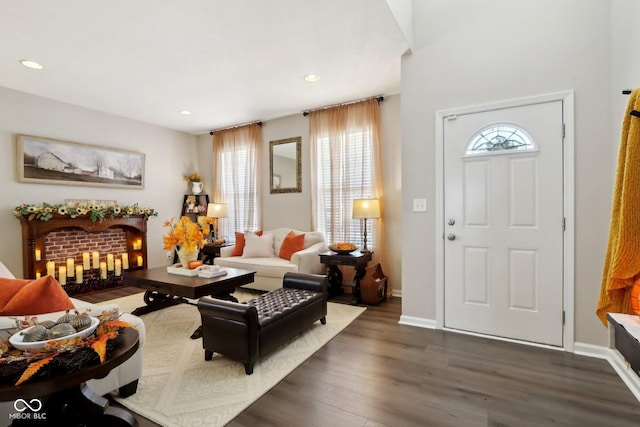 foyer featuring a brick fireplace, dark wood-type flooring, and a wealth of natural light