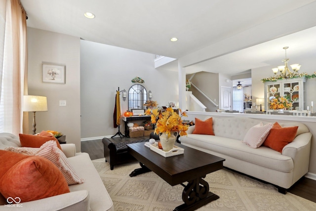 living room with ceiling fan with notable chandelier and light hardwood / wood-style floors