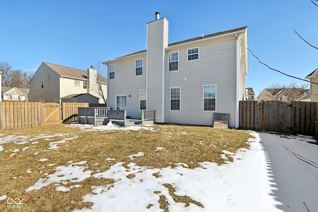 snow covered back of property with a deck