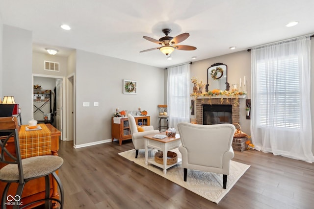 living room with dark wood-type flooring, plenty of natural light, and a brick fireplace