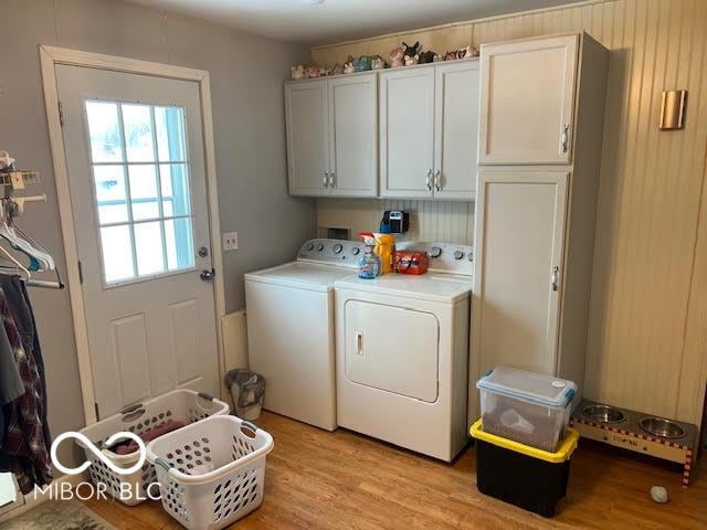 washroom featuring light wood-type flooring, washing machine and dryer, and cabinets