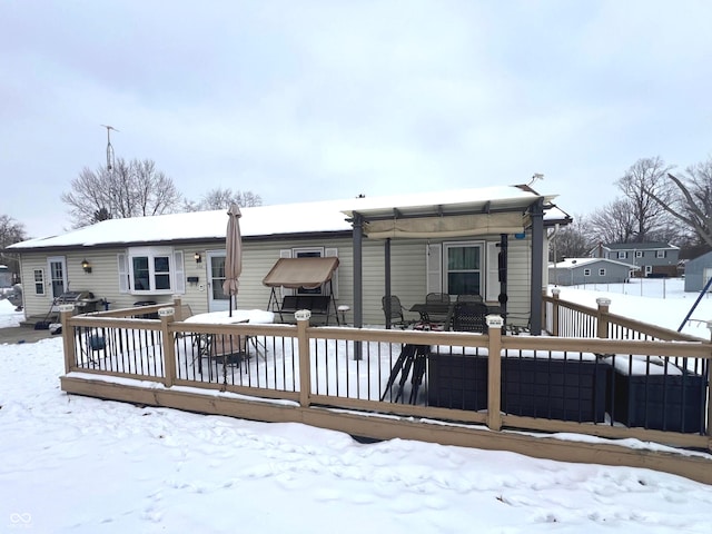 snow covered back of property featuring a wooden deck