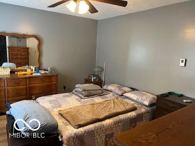 bedroom featuring ceiling fan, hardwood / wood-style floors, and a textured ceiling