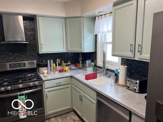 kitchen featuring light hardwood / wood-style floors, stainless steel appliances, backsplash, wall chimney range hood, and sink