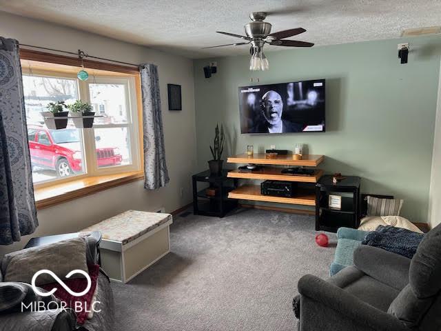 carpeted living room featuring ceiling fan and a textured ceiling