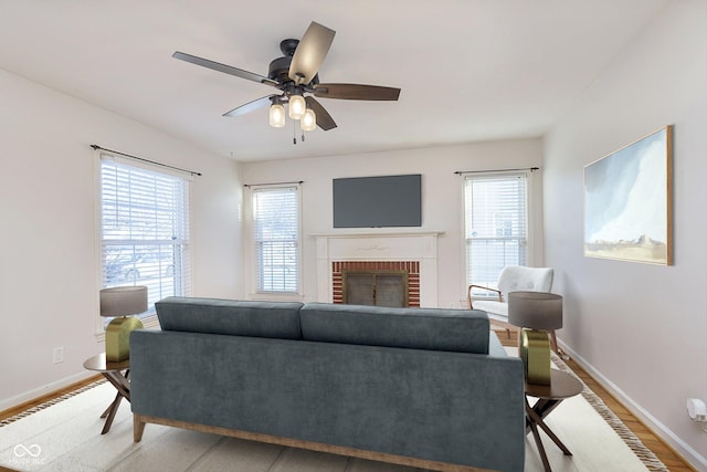 living room with a brick fireplace, a wealth of natural light, hardwood / wood-style flooring, and ceiling fan