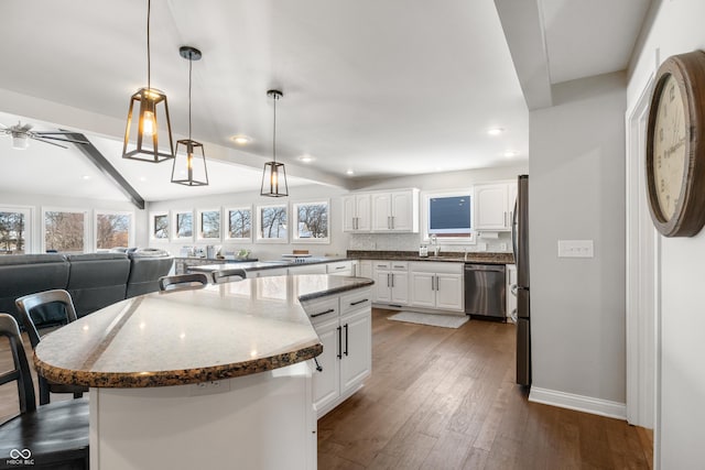 kitchen with stainless steel appliances, a kitchen island, white cabinetry, a kitchen breakfast bar, and dark wood-style floors