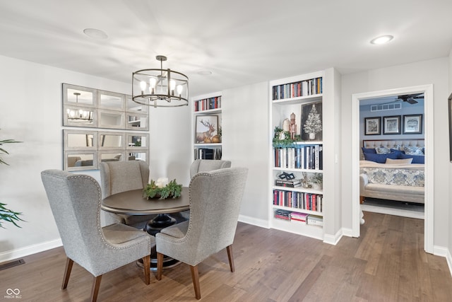 dining area with baseboards, visible vents, an inviting chandelier, and wood finished floors