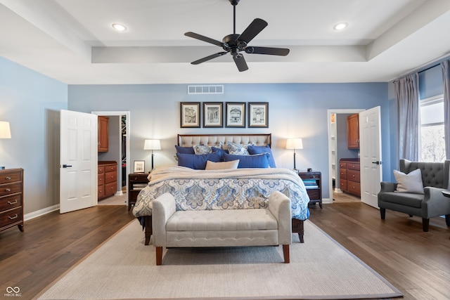 bedroom featuring dark hardwood / wood-style floors, ceiling fan, and a raised ceiling