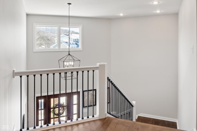 stairs featuring an inviting chandelier and wood-type flooring