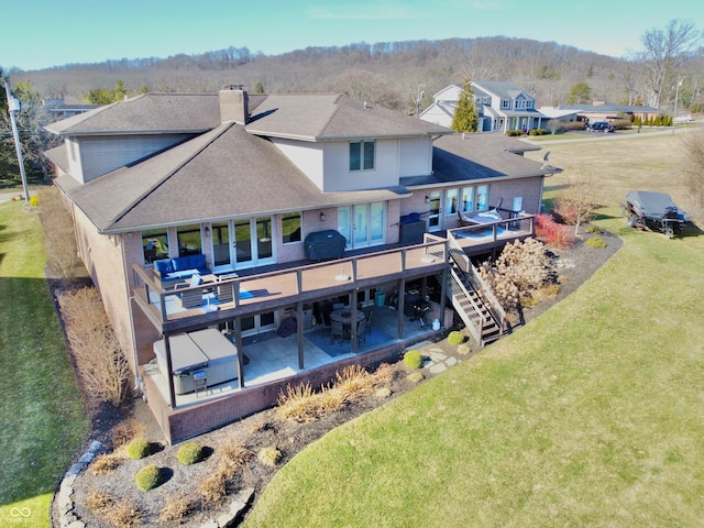 rear view of property featuring stairs, a yard, a wooden deck, a chimney, and a patio area