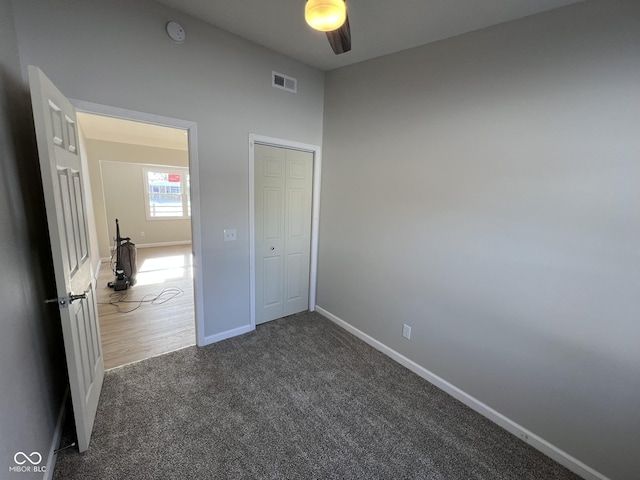 unfurnished bedroom featuring ceiling fan, a closet, and dark colored carpet