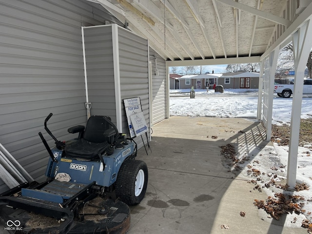 snow covered patio featuring a carport