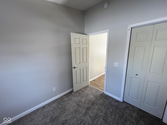 unfurnished bedroom with dark colored carpet and a closet