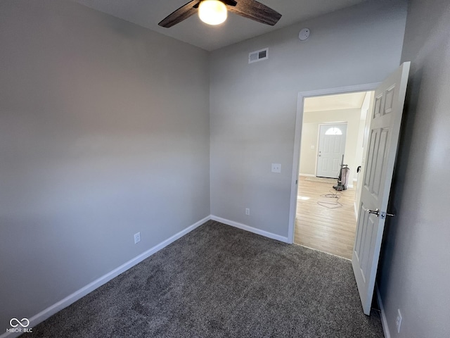 spare room with ceiling fan and dark carpet