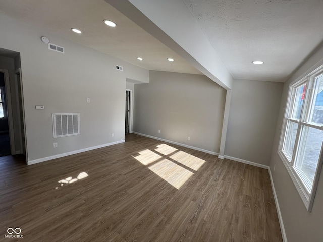 spare room with a textured ceiling and dark hardwood / wood-style flooring