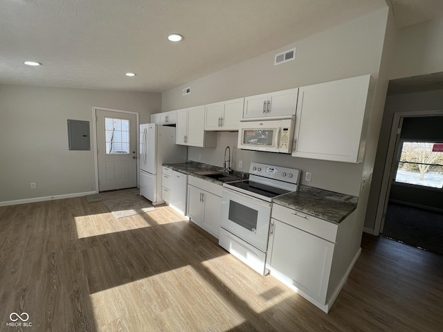 kitchen featuring sink, white cabinetry, vaulted ceiling, hardwood / wood-style flooring, and white appliances