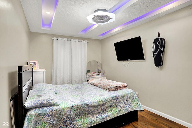 bedroom with ceiling fan, a textured ceiling, and dark hardwood / wood-style flooring