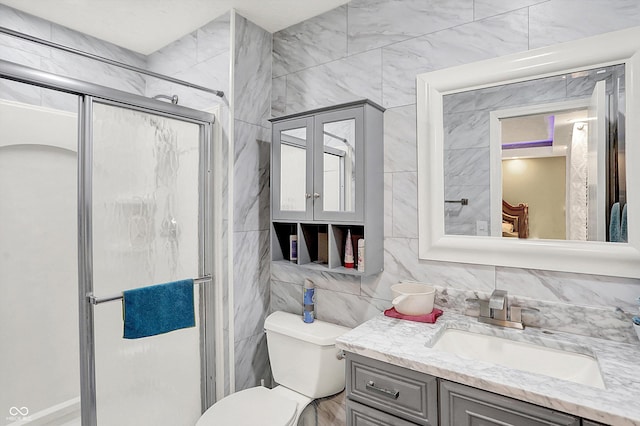 bathroom with vanity, toilet, tile walls, and an enclosed shower