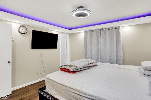 bedroom with a raised ceiling and dark hardwood / wood-style flooring