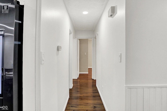 corridor featuring a textured ceiling and dark wood-type flooring