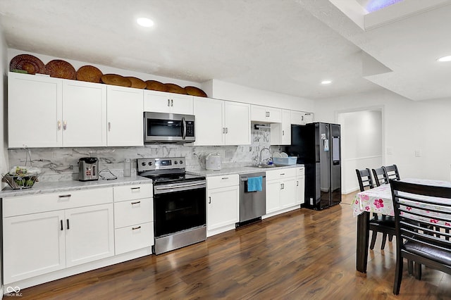 kitchen featuring appliances with stainless steel finishes, decorative backsplash, white cabinetry, and light stone countertops